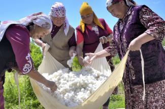 Four women around sheet full of cotton
