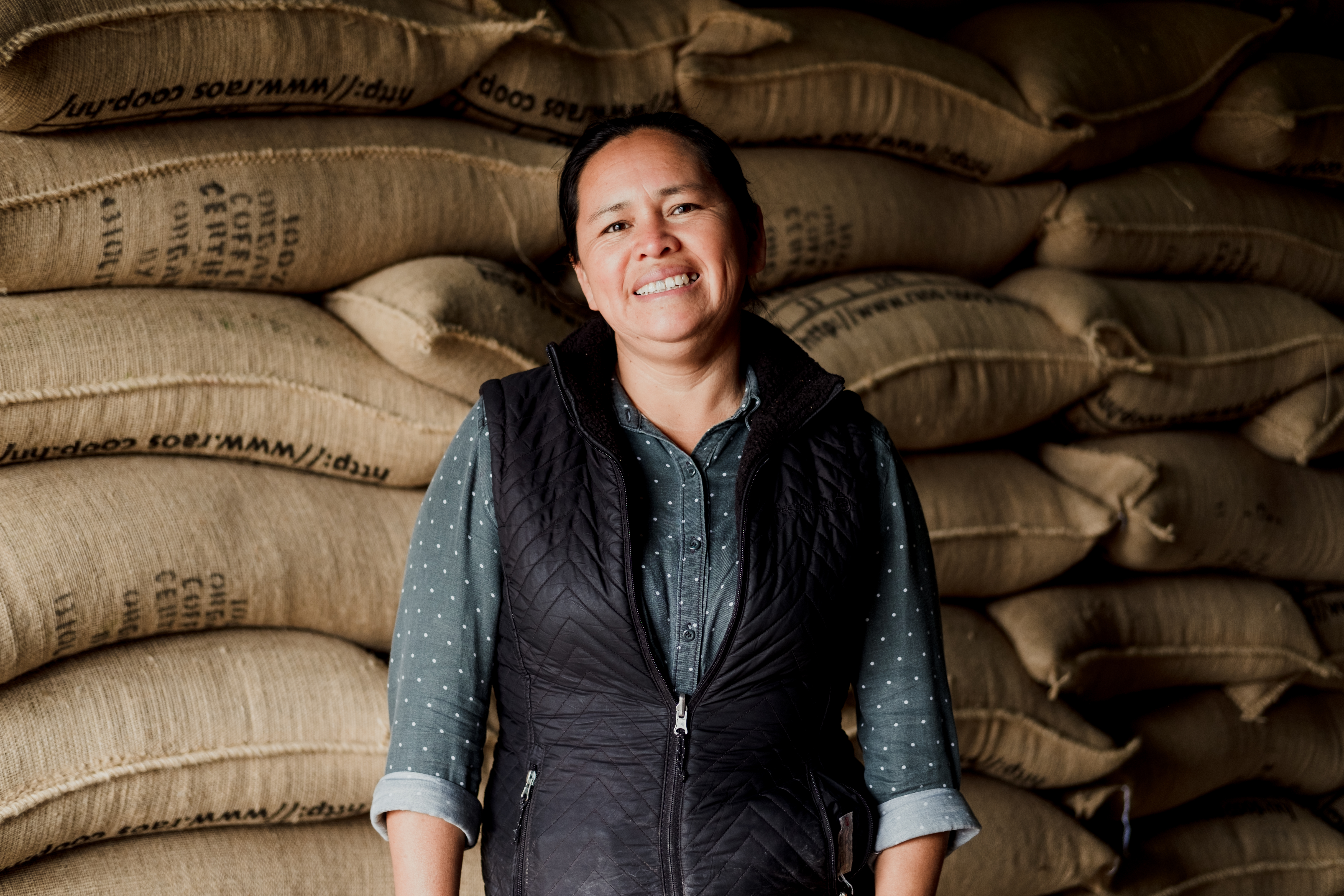 Woman standing in front of coffee bean sacks