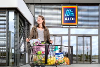 Woman with shopping cart in front of ALDI store